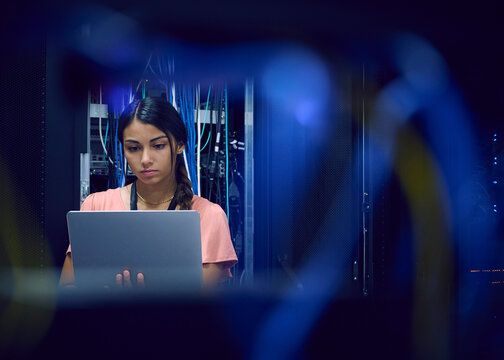 Female technician using laptop in server room 