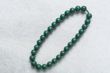 Overhead view of green vintage necklace on marble jewelry holder, top view of vintage green beaded necklace on a white background
