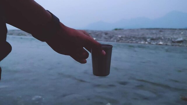 Holding a steel cup of coffee in the evening at Torsa river valley in Cooch Behar, West Bengal, India in May 2024....