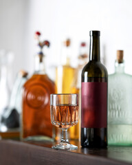 Glass of rose wine and open wine bottle with burgundy label in home mini bar. Aperitif. Luxury liquor. Wine tasting. Alcohol beverages. Drink concept. Copy space.