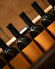 Dark glass of wine bottles with yellow labels on wooden shelves in wine cellar. Liquor store window. Corked bottles of alcohol. Drink concept. Wine beverage. Winemaking, winery. Copy space.