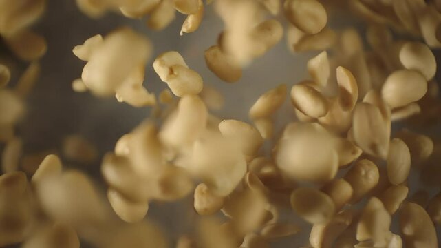 Top view of crispy roasted salted peanuts falling in super slow motion close up. Hot delicious fried peanuts snacks with smoke flying. High speed 1000 fps vertical video