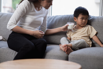 Adorable Asian baby boy refusing his mouth facing away from milk sign for refuse drinking cow milk...