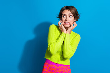 Portrait of terrified girl arms touch cheeks grin teeth look empty space isolated on blue color...