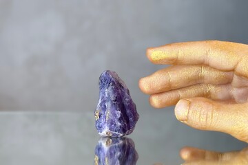 
Close-up hand trying to touch amethyst crystal on grey abstract background. Mystical atmosphere in...
