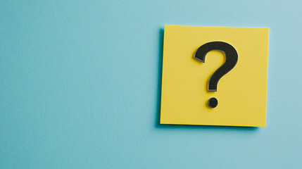 Black question mark on a yellow sticky note against a light blue paper background