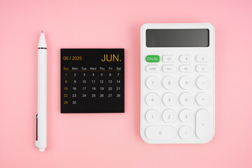 June 2025 calendar and white calculator with pen on pink background.