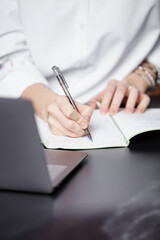 Young business woman or university student holding pen and papers making notes in documents on the table. Shallow depth of field. Focus on a tip of the pen.