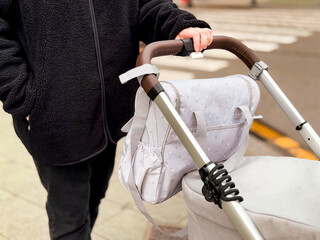 Caucasian female adult with baby stroller and diaper bag on city street
