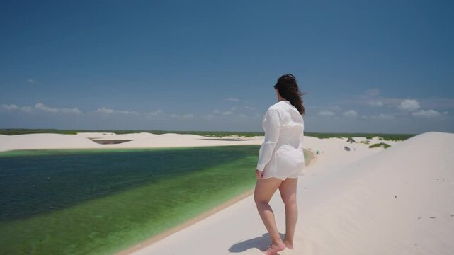Panorama landscape of woman on desert dunes between rain water lagoons. Brazil Northeast.
