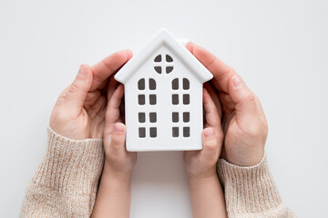 Caucasian hands holding ceramic house model representing home safety and security