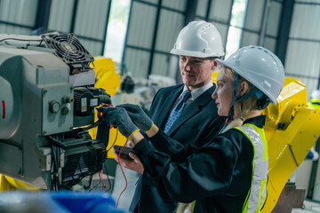 Engineer and technician inspect machinery in a manufacturing facility during daytime operations