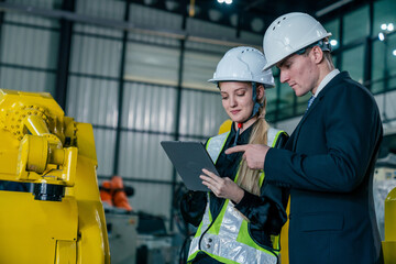 Fototapeta premium Engineers review industrial processes together while utilizing a tablet in a modern factory setting