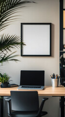 A blank black picture frame is hanging on the wall of an office with a modern desk, laptop, and chair
