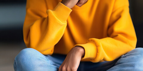 Person Seated Wearing Yellow Sweatshirt and Blue Jeans