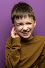 Child holding ear, wincing in pain, purple background. Ideal for themes of earache, childhood health issues, and expressions of discomfort.