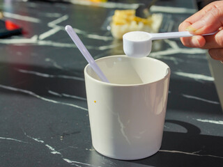 Lifestyle Health care. Hands of a person scooping collagen powder from a jar with a scoop. Collagen, which contains vitamins, helps nourish, anti age and restore the body's deterioration.