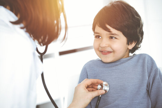 Doctor-woman examining a child patient by stethoscope in sunny clinik. Medicine concept