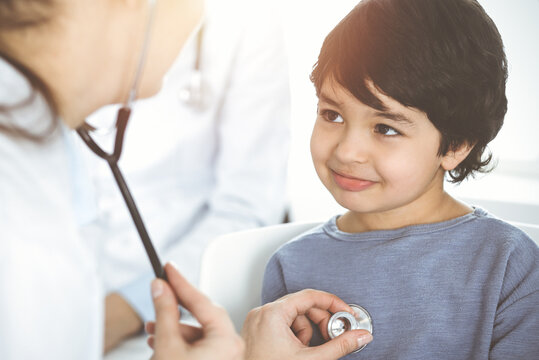 Doctor-woman examining a child patient by stethoscope in sunny clinik. Medicine concept