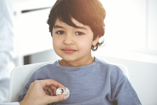 Doctor-woman examining a child patient by stethoscope in sunny clinik. Medicine concept