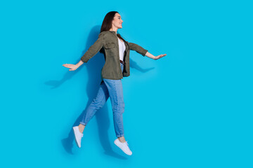Obraz premium Young woman in casual outfit jumping happily on a bright blue background