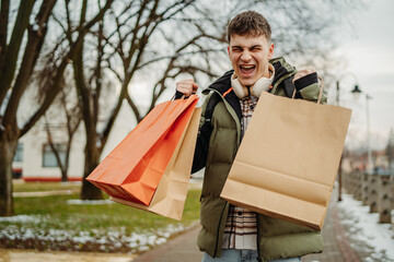 Young man student smiling walk home from shopping with shopping bags