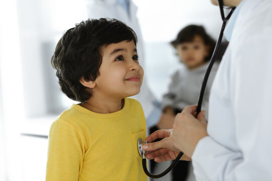 Woman-doctor examining a child patient by stethoscope. Cute arab boy at physician appointment. Medicine help concept