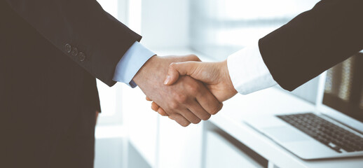 Obraz premium Businessman and woman shaking hands in office. Concept of handshake as success symbol in business