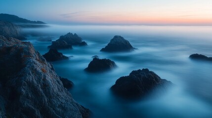 Coastal rocks shrouded in fog at sunset.  Possible use Stock photo