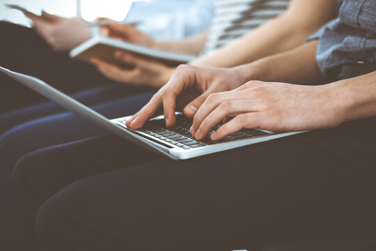 Group of casual dressed business people working at meeting or conference, close-up of hands. Businessman using laptop computer. Teamwork or coaching concept