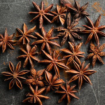 Star anise spices on a black and gray marbled background, top view.