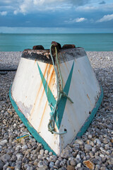 Hölzernes Fischerboot, grün und weiß in Yport, Normandie mit Meer und dramatischem Himmel