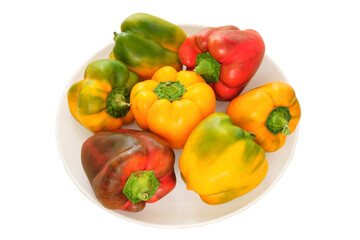 Peppers in a porcelain plate. Orange and red ripe vegetables. Isolate on white background. Top view.