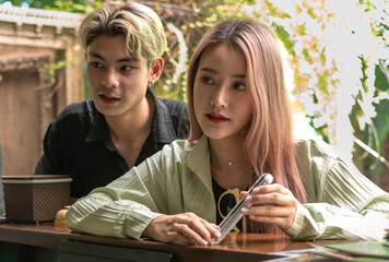 Young modern Asian tourist couples using smartphone check in hotel at reception desk after booking online