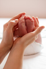 Parent holding in the hands feet of a newborn baby. Mom holding baby's feet 