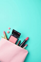 Pink cosmetic bag overflowing with makeup essentials against a vibrant teal backdrop
