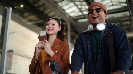 Happy asian couple walking through the airport terminal with luggage, using a smartphone at the boarding gate to checking time flight and ready for their vacation trip.
 - Powered by Adobe
