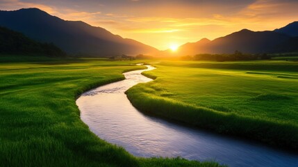 Fototapeta premium A beautiful sunrise over a serene river flowing through lush green fields, surrounded by majestic mountains. The tranquil scene captures the essence of nature's beauty and peace.