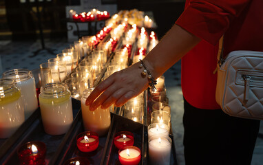 Woman putting candle near altar in church.