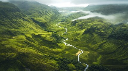 High-angle view of lush green valley with winding river, misty mountains. Potential use Stock photo