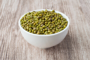 Mung beans in a bowl on a wooden background, horizontal.