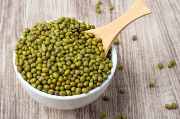 Mung beans in a bowl and spoon on a wooden background, horizontal..