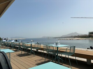 Obraz premium modern bar stools and tables overlooking the serene blue sea