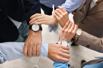 Teamwork. Group of people holding hands together indoors, top view