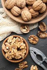 Fresh ripe walnuts, nutcracker and shells on black table, flat lay