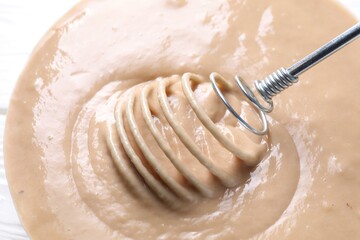 Whisk and bowl of dough, closeup view