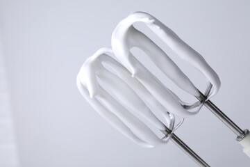 Whisks with whipped cream on white background, closeup