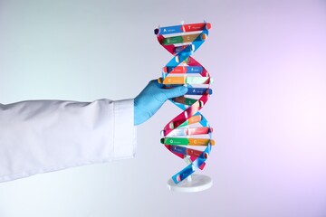 Scientist with DNA structure model on color background, closeup