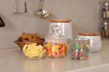 Tasty gummy candies on white table in kitchen