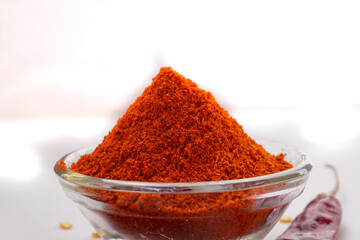 Bowl with red chili powder on white background. Selective focus.